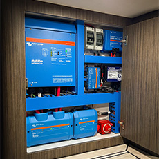 Organized van cabinet montrant Victron inverters, chargers, and marine wiring layout